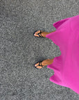 Black kitten heel sandals worn with a pink dress on gravel