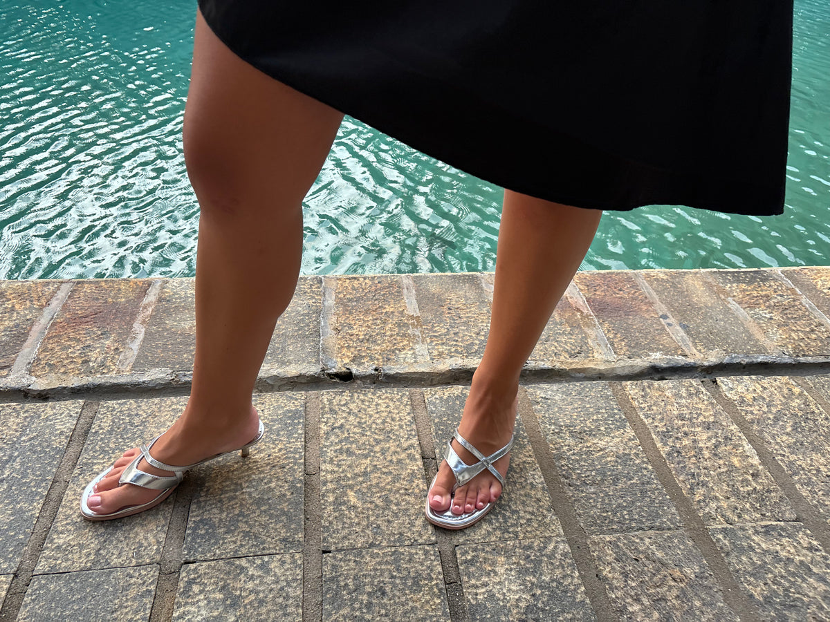 Silver kitten heel sandals worn with a black skirt