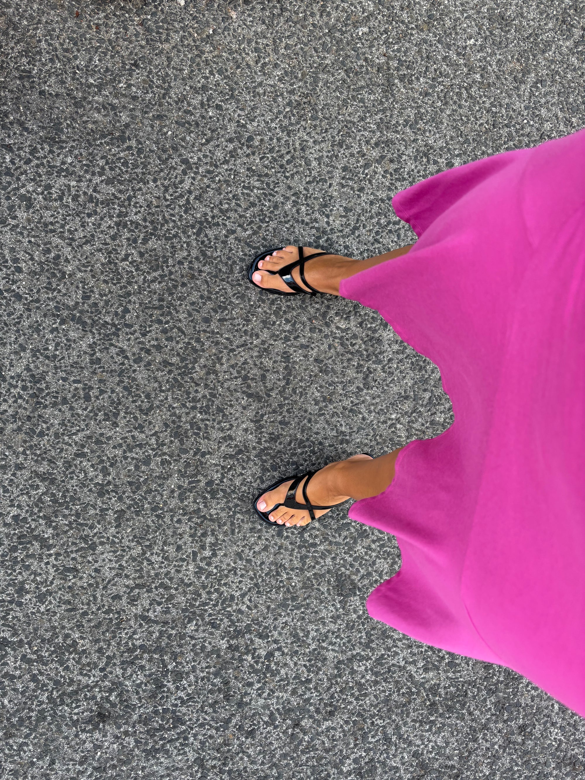 Black kitten heel sandals worn with a pink dress on gravel