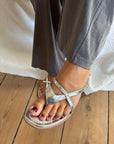 Silver kitten heel sandals worn with grey wide-leg trousers